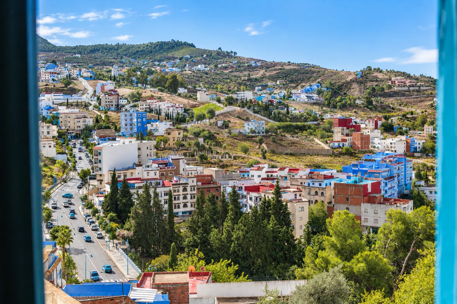 Edificios de Chefchaouen y colinas verdes vistos desde una ventana.